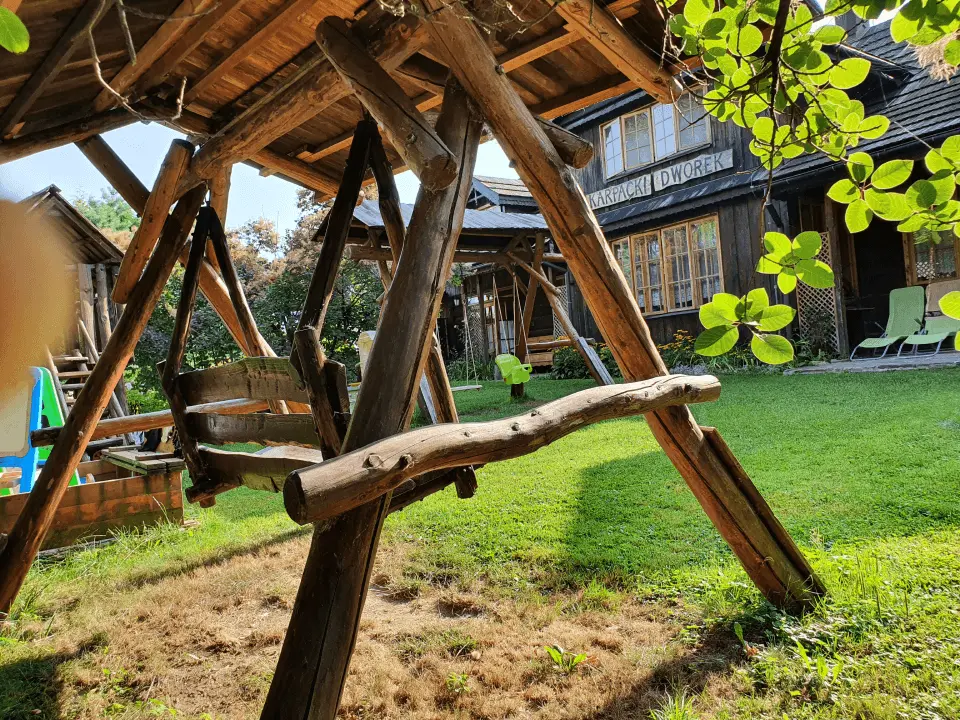 Drewniana huśtawka położona w ogrodzie karpackiego dworku