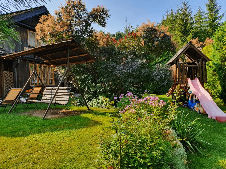 Wejście do karpackiego dworku od strony ogrodu oraz dwa rozłożone leżaki