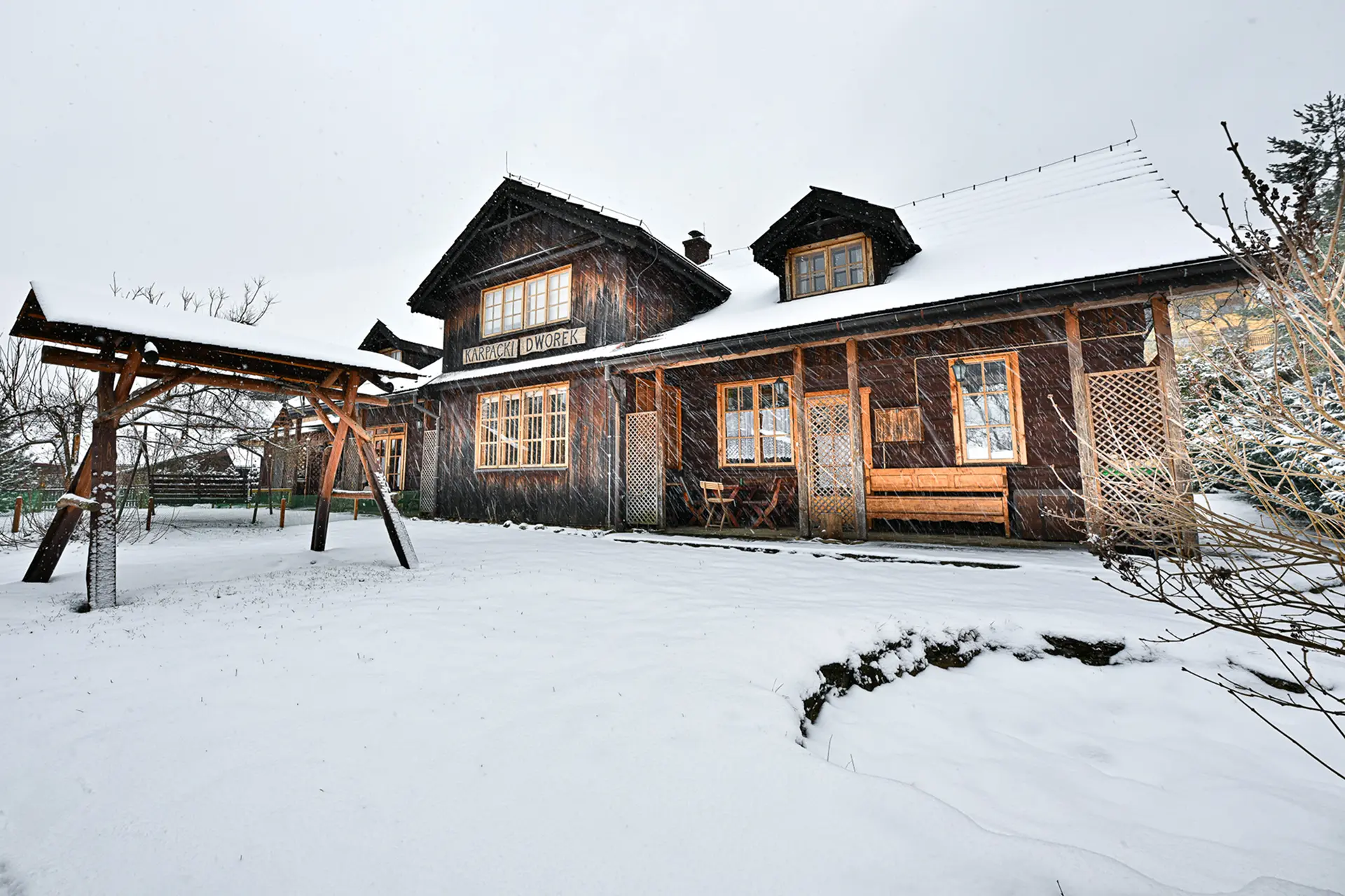 Wejście do karpackiego dworku od strony ogrodu oraz dwa rozłożone leżaki