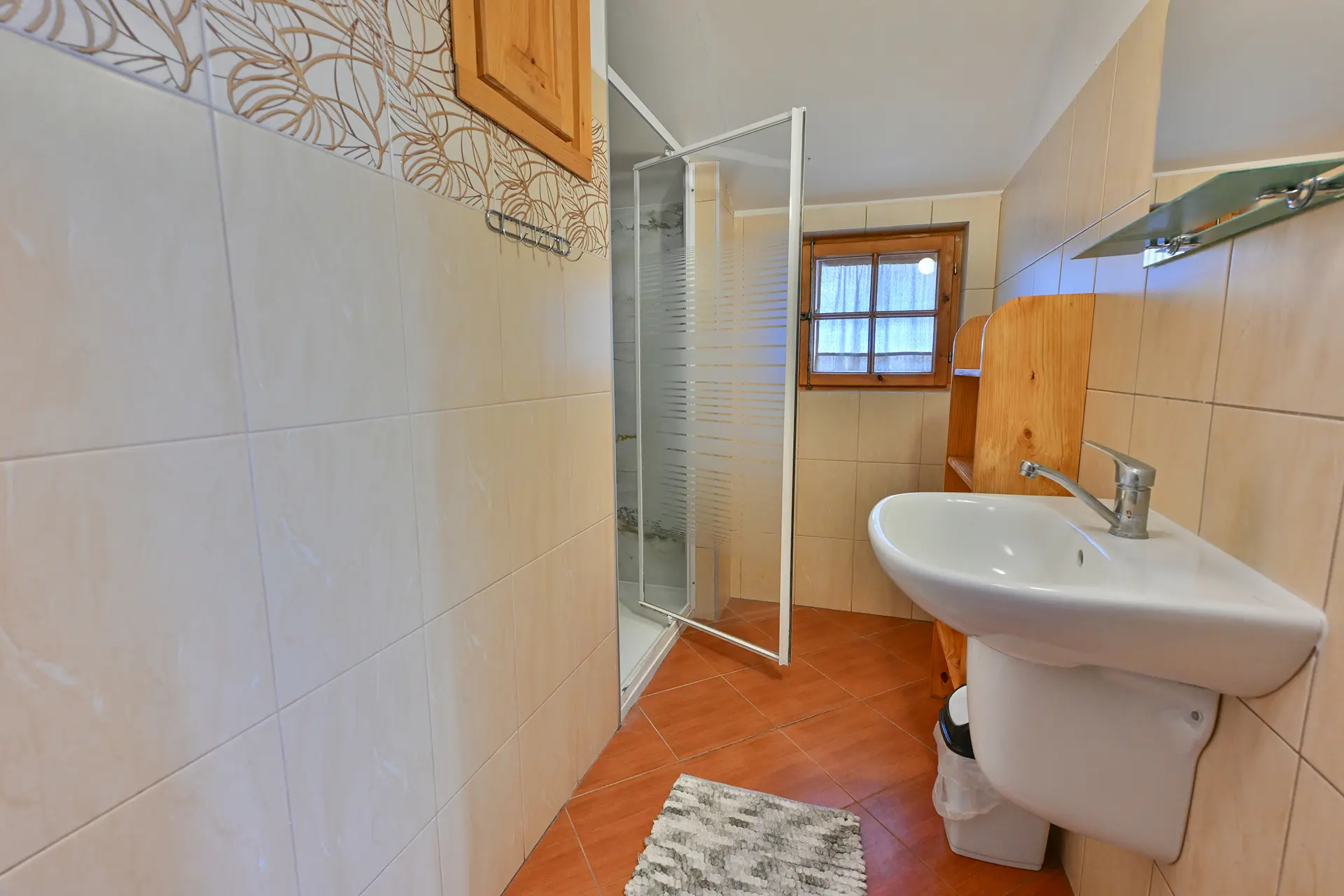 Łazienka z kabiną prysznicową, oknem i umywalką