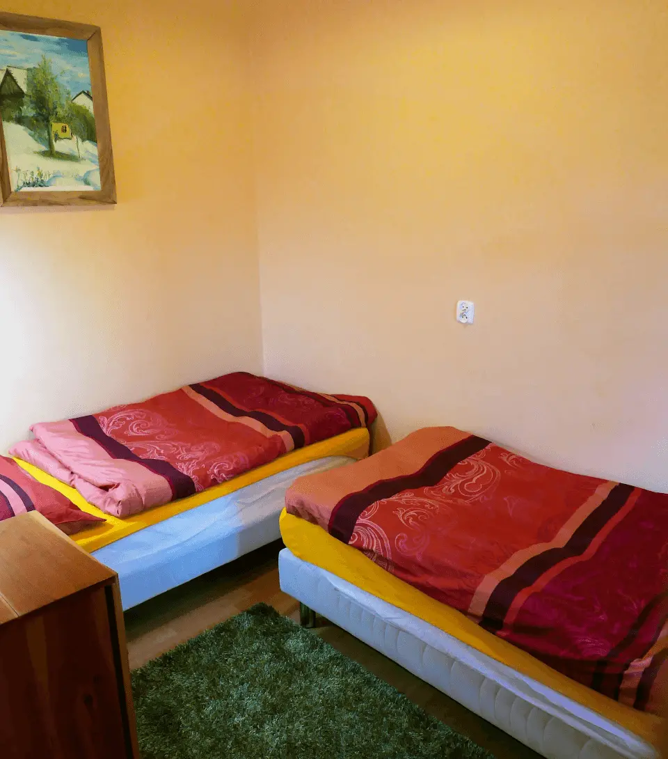 Sypialnia z dwoma łóżkami, gniazdkiem, szafką oraz powieszonym na ścianie obrazem