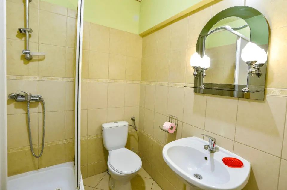 Łazienka z kabiną prysznicową, umywalką, lustrem oraz toaletą.